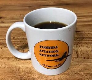 A coffee mug with the florida aviation network logo on it.