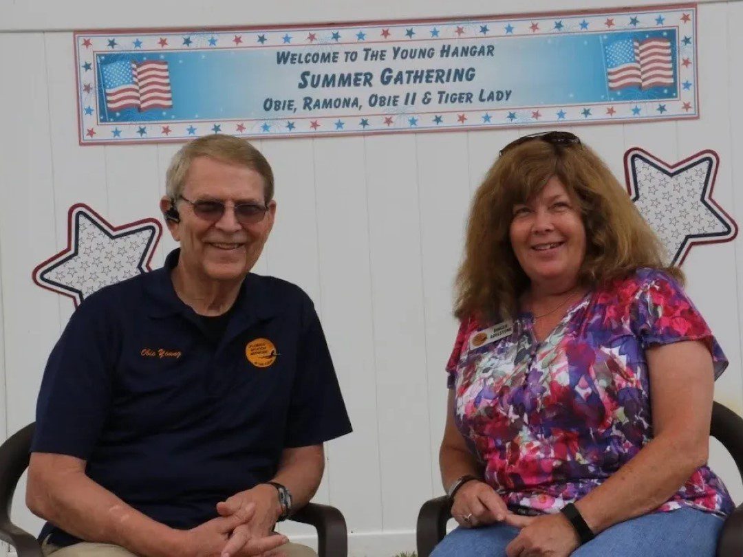 A man and woman sitting in front of an american flag.
