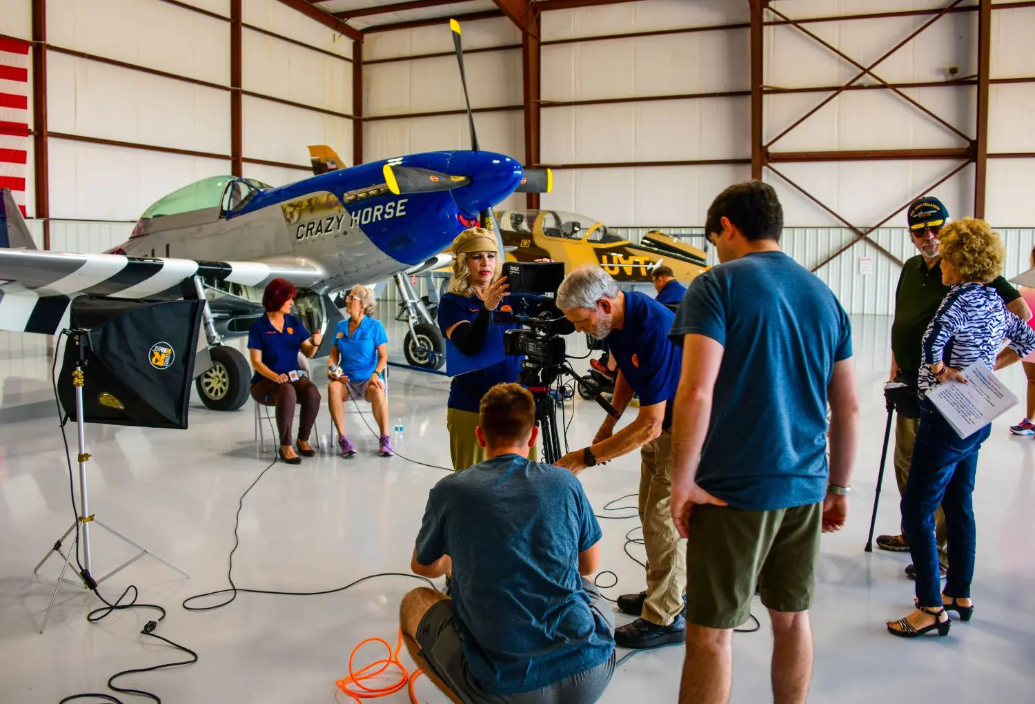 A group of people standing around in an airplane hangar.