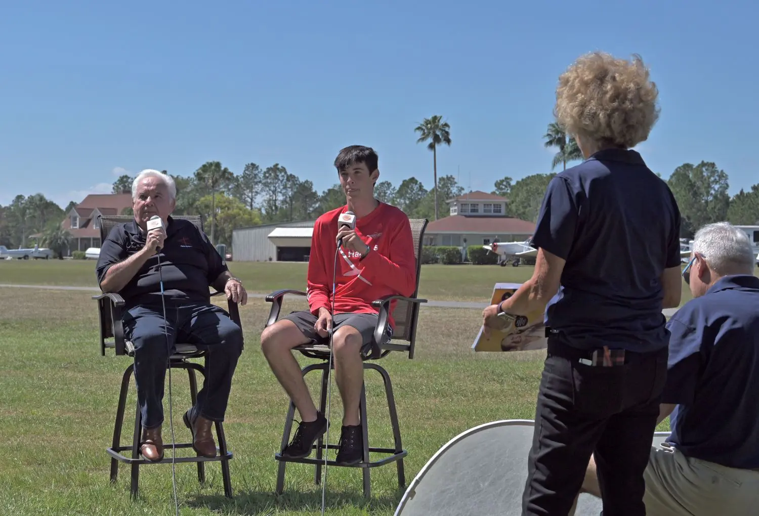 A group of people sitting on stools in the grass.