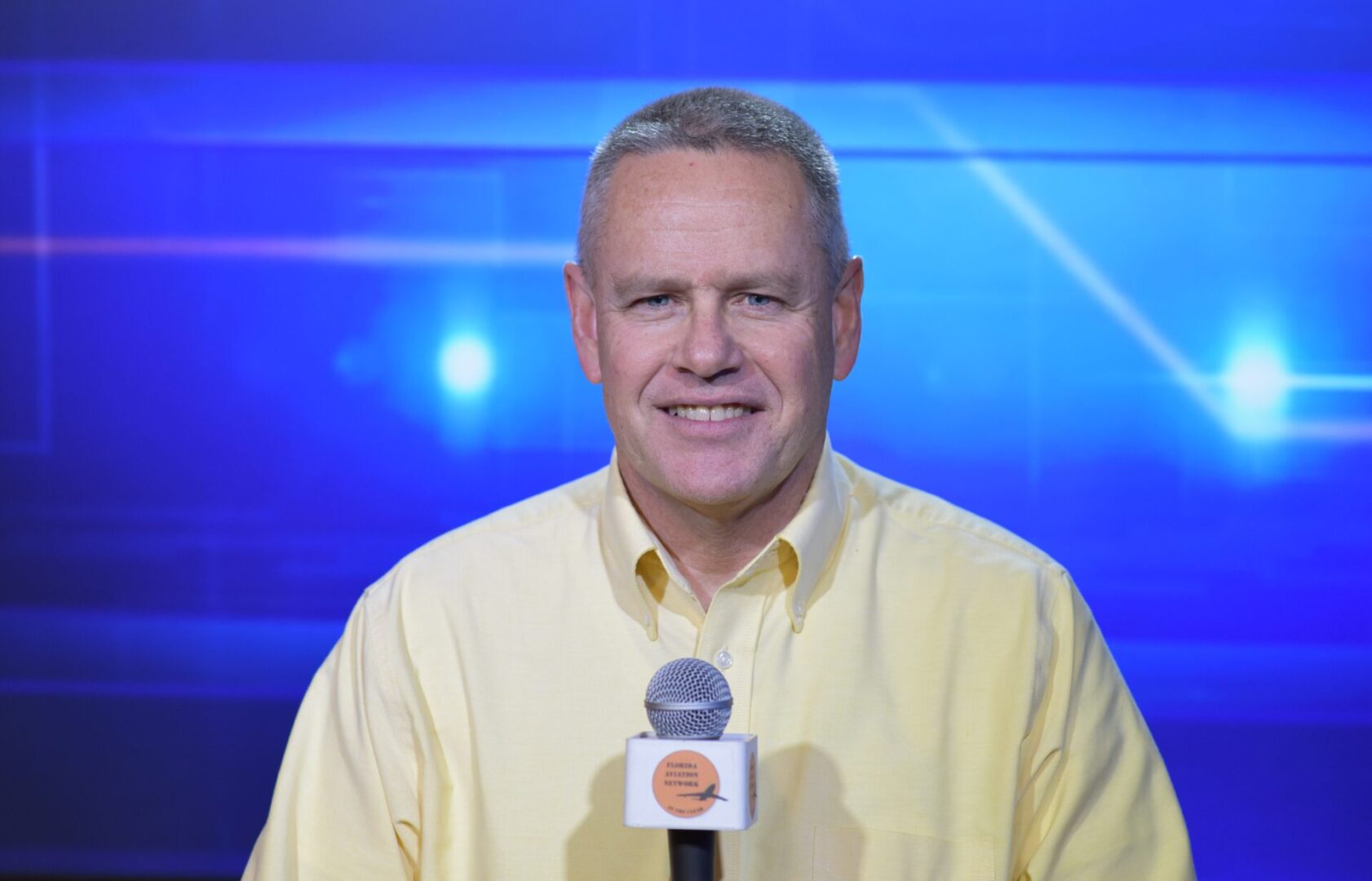 A man in yellow shirt holding a microphone.