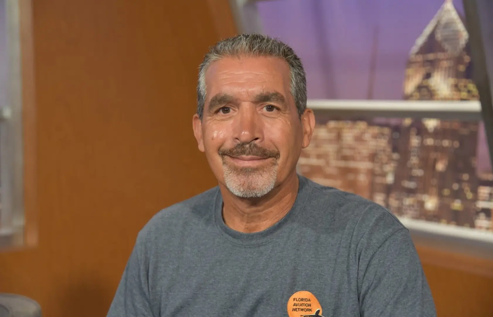 An elder man wearing a gray tshirt smiling
