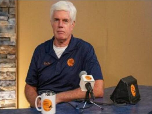 Man sitting at table with microphone.