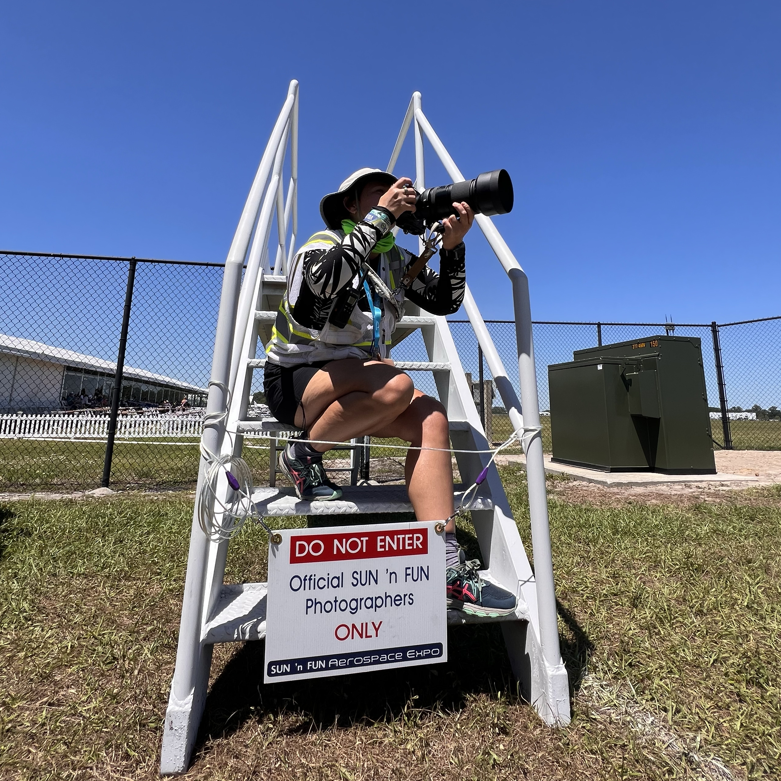 Event photographer on ladder with telephoto lens