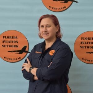 Woman posing with Florida Aviation Network backdrop.