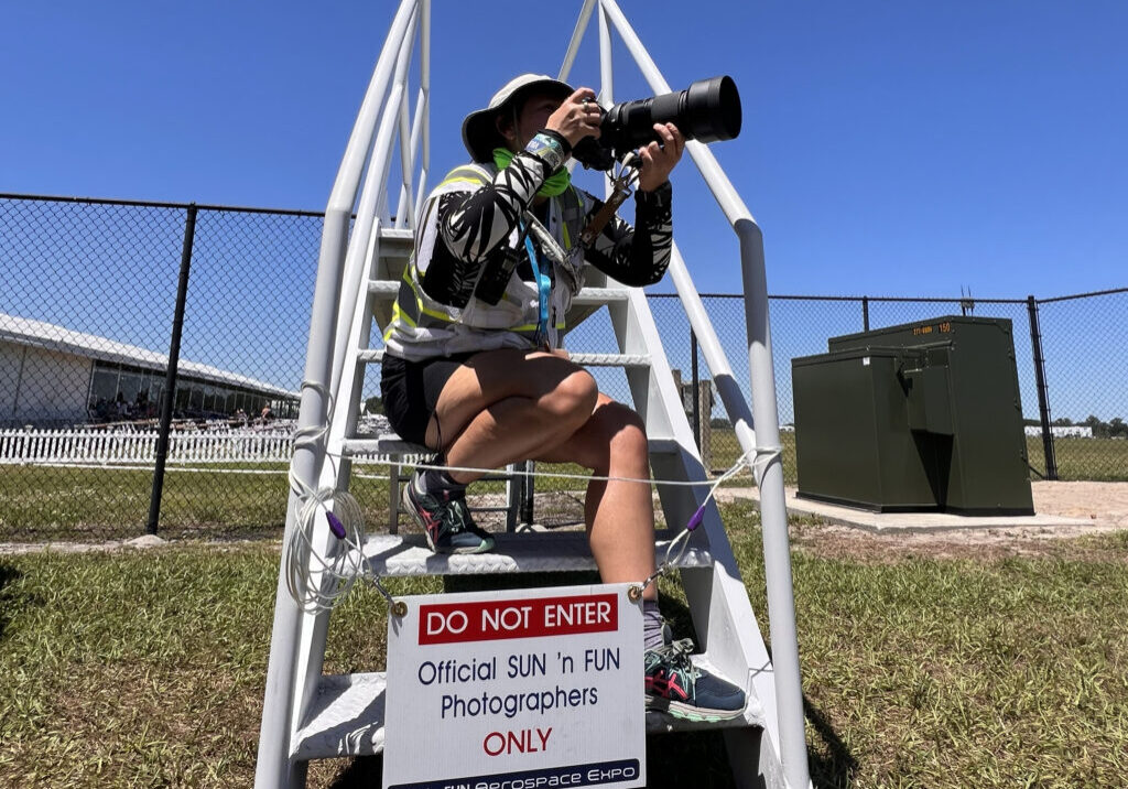 Event photographer on ladder with telephoto lens
