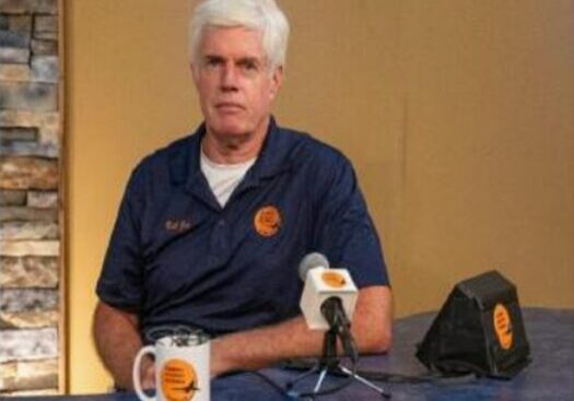 Man sitting at table with microphone.